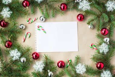 Çam dalları üzerinde kırmızı ve gümüş top ve rustik bej renkli arka plan üzerinde kar taneleri ile şenlikli Noel sınır