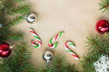 Çam dalları üzerinde kırmızı ve gümüş top ve rustik bej renkli arka plan üzerinde kar taneleri ile şenlikli Noel sınır