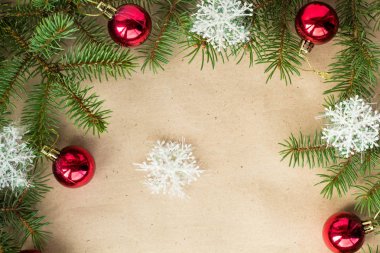 Çam dalları üzerinde kırmızı topları ve rustik bej renkli arka plan üzerinde kar taneleri ile şenlikli Noel sınır