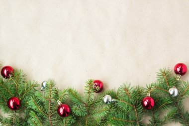 Çam dalları üzerinde kırmızı ve gümüş top ve rustik bej renkli arka plan üzerinde kar taneleri ile şenlikli Noel sınır
