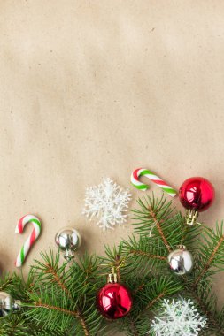 Çam dalları üzerinde kırmızı ve gümüş top ve rustik bej renkli arka plan üzerinde kar taneleri ile şenlikli Noel sınır