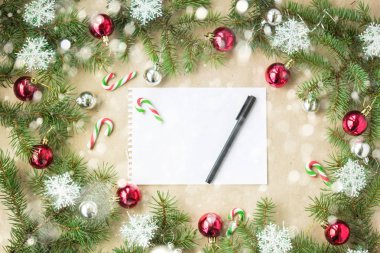 Kırmızı toplarla rustik bej renkli arka plan üzerinde kar köknar dalları ve kar taneleri ile şenlikli Noel sınır