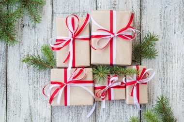 Noel hediye kutuları çam dalları ile ahşap arka plan üzerinde kırmızı ve Beyaz kurdele ile.