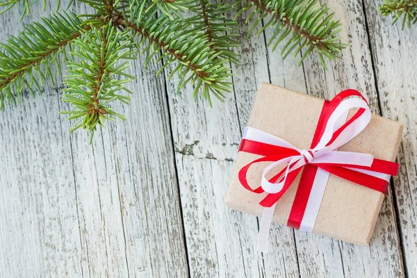 Border of Christmas gift boxes and fir tree branch on wooden table.