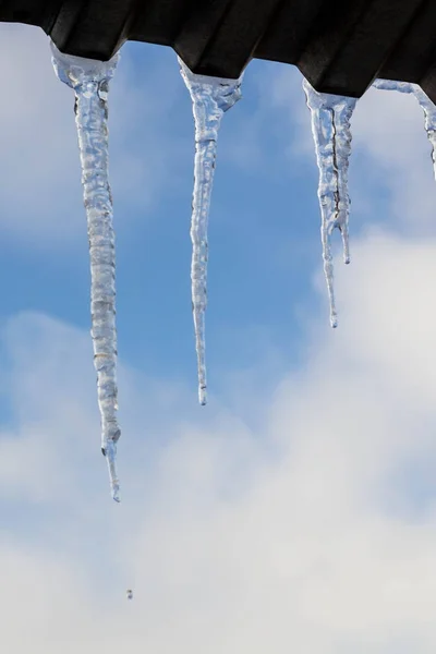 Ghiaccioli appesi sul tetto d'inverno. Formazione di ghiaccio naturale di cristalli di ghiaccio appesi sul bordo del tetto in inverno — Foto Stock