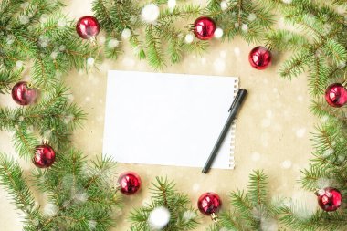 Kırmızı toplarla rustik bej renkli arka plan üzerinde kar köknar dalları ve kar taneleri ile şenlikli Noel sınır