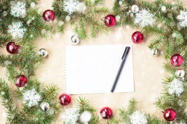 Kırmızı toplarla rustik bej renkli arka plan üzerinde kar köknar dalları ve kar taneleri ile şenlikli Noel sınır