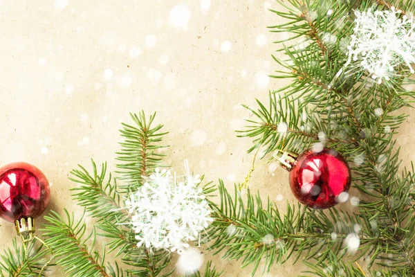 Kırmızı toplarla rustik bej renkli arka plan üzerinde kar köknar dalları ve kar taneleri ile şenlikli Noel sınır