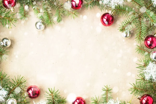 Kırmızı toplarla rustik bej renkli arka plan üzerinde kar köknar dalları ve kar taneleri ile şenlikli Noel sınır
