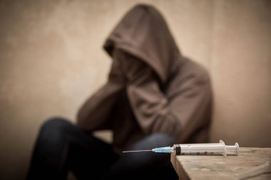 Arka planda oturan odak adam uyuşturucu bağımlısı dışarı ile şırınga