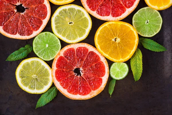 Esquina con rebanada de naranjas, limones, limas, pomelo y patrón de menta en negro. Puesta plana — Foto de Stock