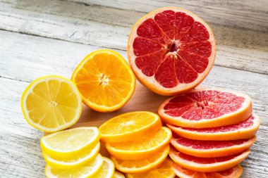 Taze narenciye - limon, greyfurt, portakal ahşap kesme tahtası bir bıçakla dilimlenmiş.