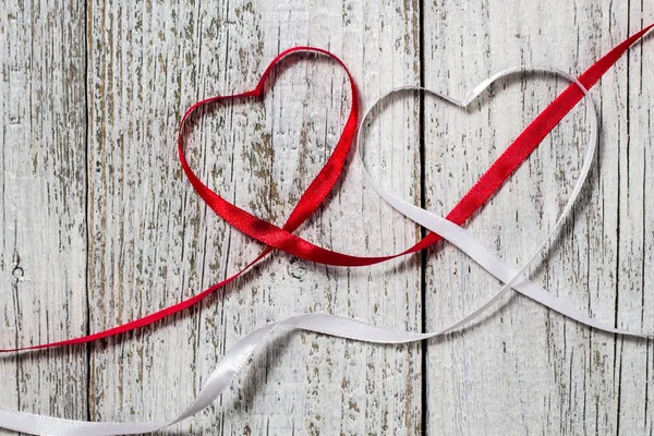 Red and white ribbon hearts for valentines day on wooden background.
