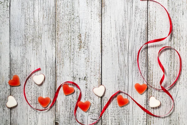 Marmeládu candy tvar srdce a červenou stužkou na dřevěný stůl, valentine den složení, blahopřání — Stock fotografie