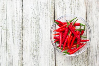 Beyaz ahşap arka plan şeffaf kase içinde üstten görünüm kırmızı biber biber.