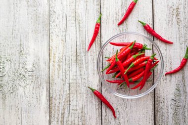 Beyaz ahşap arka plan şeffaf kase içinde üstten görünüm kırmızı biber biber.