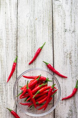 Beyaz ahşap arka plan şeffaf kase içinde üstten görünüm kırmızı biber biber.
