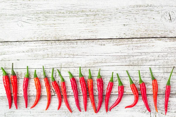 frame of red Chile pepper on white wooden table.