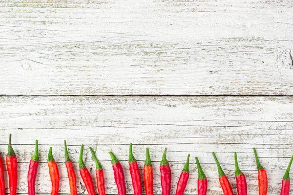 frame of red Chile pepper on white wooden table.