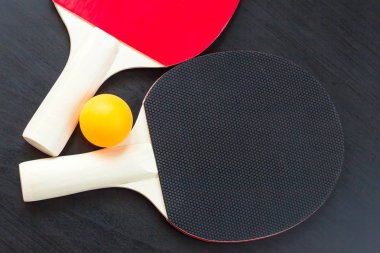 İki Masa Tenisi veya ping pong raketleri ve siyah bir arka plan üzerinde topu