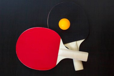 İki Masa Tenisi veya ping pong raketleri ve siyah bir arka plan üzerinde topu