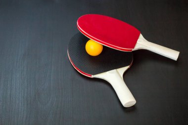 İki Masa Tenisi veya ping pong raketleri ve siyah bir arka plan üzerinde topu