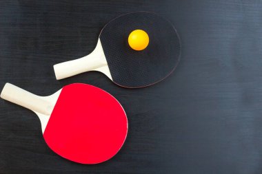 İki Masa Tenisi veya ping pong raketleri ve siyah bir arka plan üzerinde topu