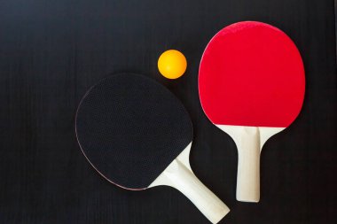 İki Masa Tenisi veya ping pong raketleri ve siyah bir arka plan üzerinde topu