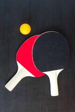İki Masa Tenisi veya ping pong raketleri ve siyah bir arka plan üzerinde topu