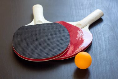 İki Masa Tenisi veya ping pong raketleri ve siyah bir arka plan üzerinde topu