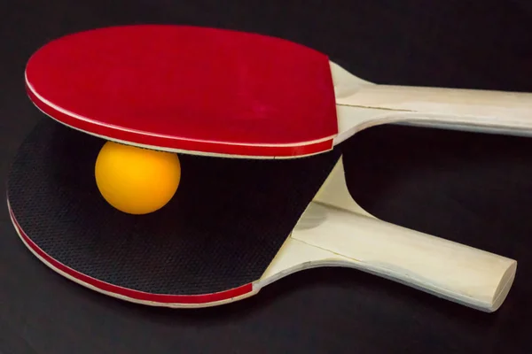 Два настільний теніс або ракетки для пінг-понг і м'яч на чорному тлі — стокове фото