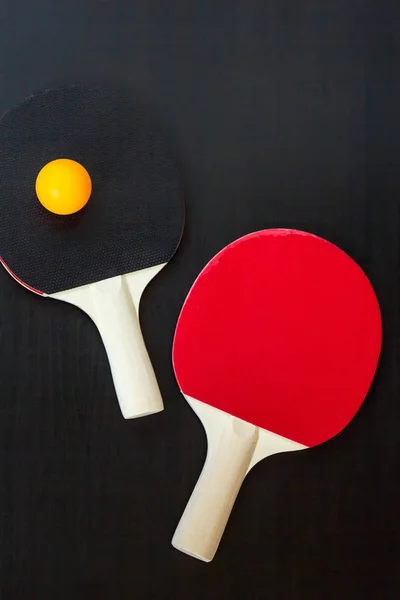 Due racchette da ping pong o da ping pong e palla su sfondo nero — Foto Stock