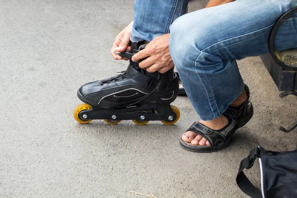 Primer plano del hombre que pone en patines al aire libre — Foto de Stock