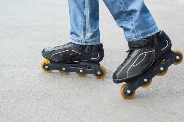 Young man in blue jeans riding roller skates in the city. Close up legs — Stock Photo, Image