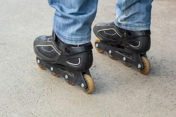 Joven en jeans azules montando patines en la ciudad. Cierra las piernas — Foto de Stock