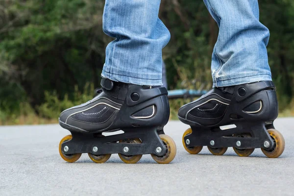 Joven en jeans azules montando patines en la ciudad. Cierra las piernas — Foto de Stock