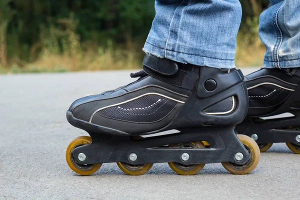 Jeune homme en jeans bleus chevauchant des patins à roulettes dans la ville. Fermer les jambes — Photo