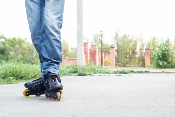 Jovem de calças de ganga azuis a andar de patins na cidade. Fechar as pernas — Fotografia de Stock