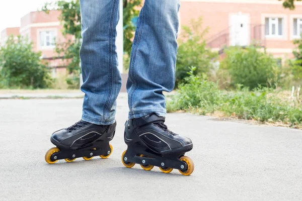 Joven en jeans azules montando patines en la ciudad. Cierra las piernas — Foto de Stock