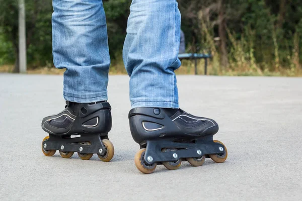 Giovane in jeans blu che cavalca pattini a rotelle in città. Chiudi le gambe — Foto Stock