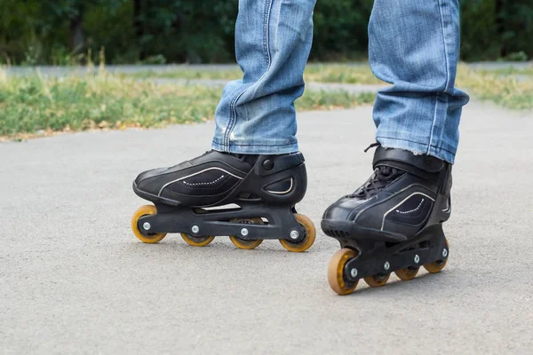 Jovem de calças de ganga azuis a andar de patins na cidade. Fechar as pernas — Fotografia de Stock