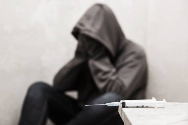 Arka planda oturan odak adam uyuşturucu bağımlısı dışarı ile şırınga