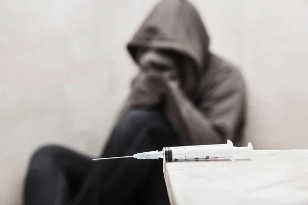 Arka planda oturan odak adam uyuşturucu bağımlısı dışarı ile şırınga