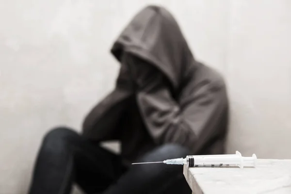 Ampułkostrzykawkę z focus człowiek narkomana siedzi w tle — Zdjęcie stockowe