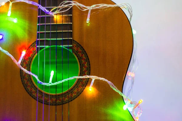 Guitare acoustique enveloppée par une guirlande colorée. Noël et Nouvel An cadeau de musique — Photo