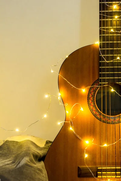 Gitara akustyczna owinięta w świecącą girlandę. Prezent gwiazdkowy — Zdjęcie stockowe