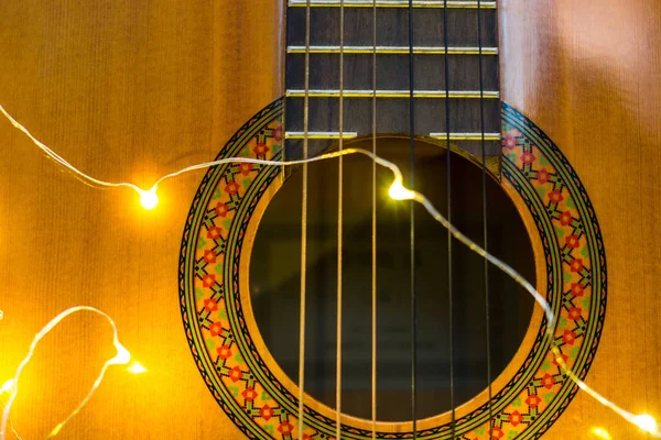 Акустична гітара, загорнута в яскраву гірлянду. Різдвяний подарунок — стокове фото
