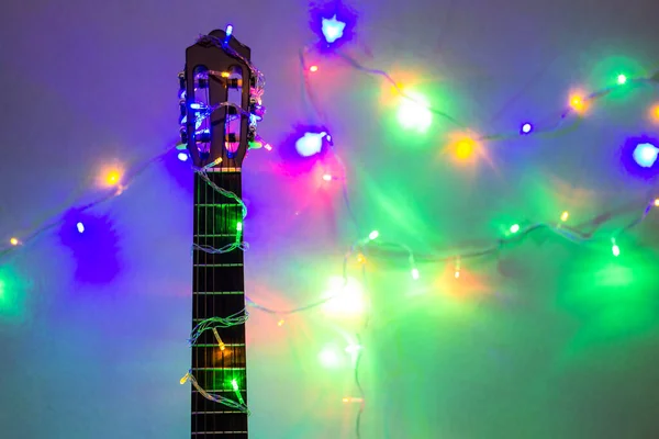 Акустическая гитара, завернутая в яркую гирлянду. Рождество и новогодний музыкальный подарок — стоковое фото
