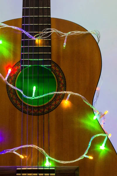 Guitare acoustique enveloppée par une guirlande colorée. Noël et Nouvel An cadeau de musique — Photo