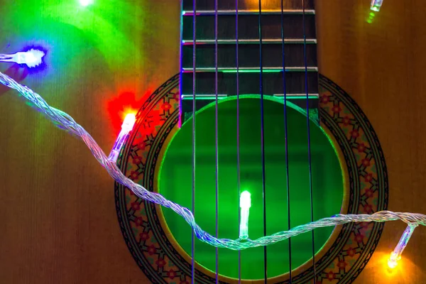 Акустическая гитара, завернутая в яркую гирлянду. Рождество и новогодний музыкальный подарок — стоковое фото